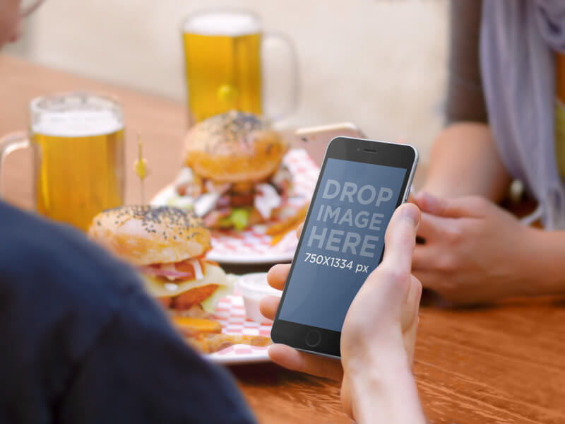 IPHONE 6 MOCKUP AT A HAMBURGER AND BEER PLACE WITH FRIENDS