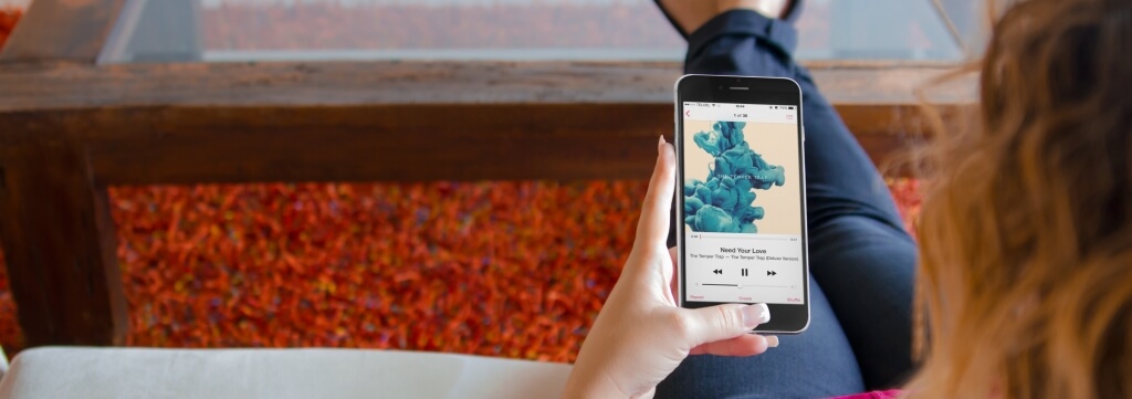 A girl sitting on a couch while holding her mockup phone by Placeit