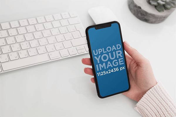 Mockup Featuring A Woman S Hand Holding An Iphone 11 Pro Over A Neat Desk