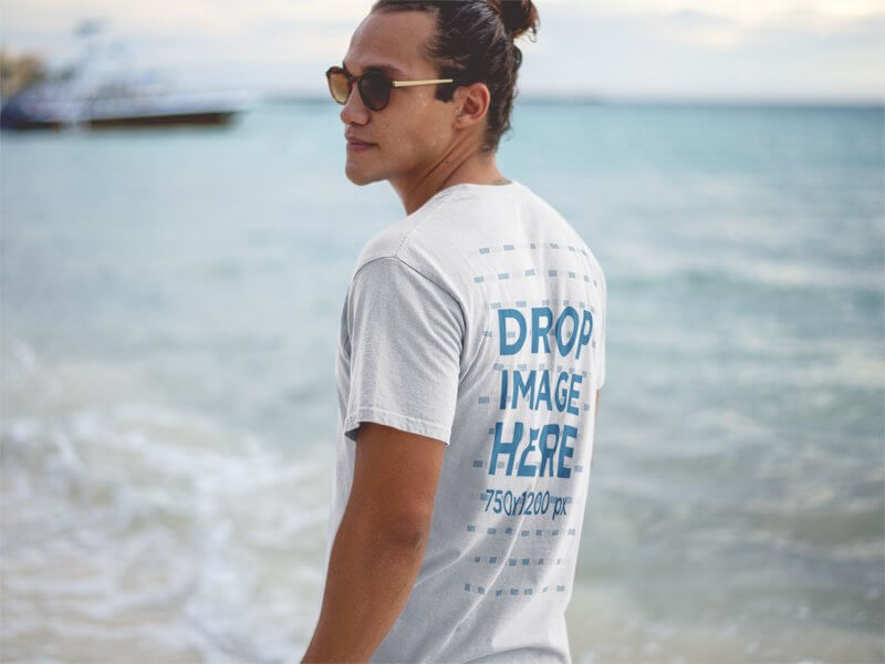 T-Shirt Mockup of a Hipster Guy Wearing Sunglasses at the Beach Shore