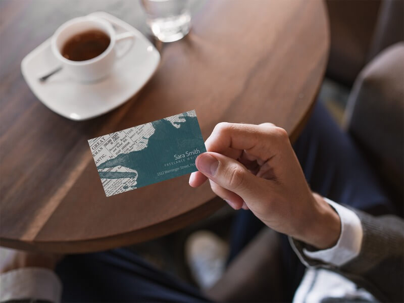 Business Card Being Held While Inside A Cafe