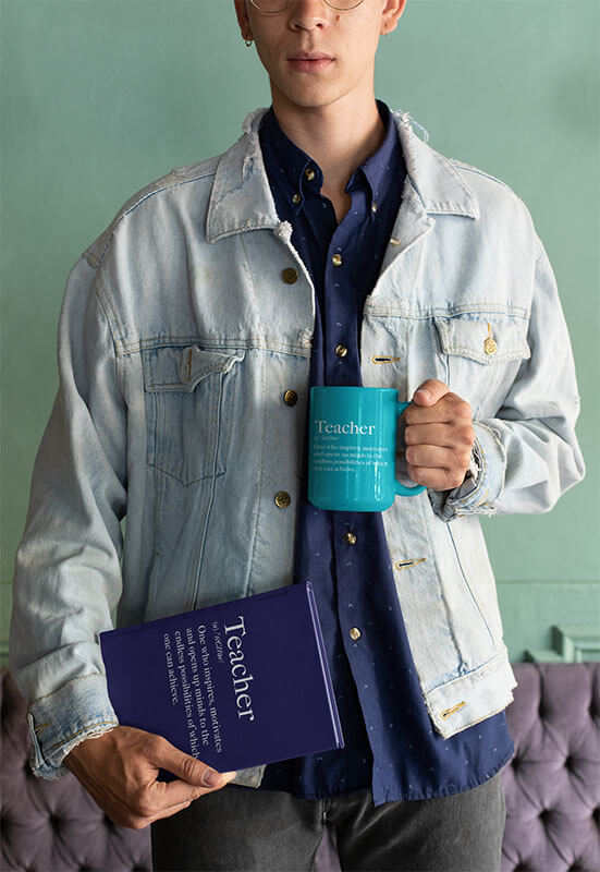 Mockup Of A Man Wearing A Denim Jacket And Holding A Coffee Mug And A Book