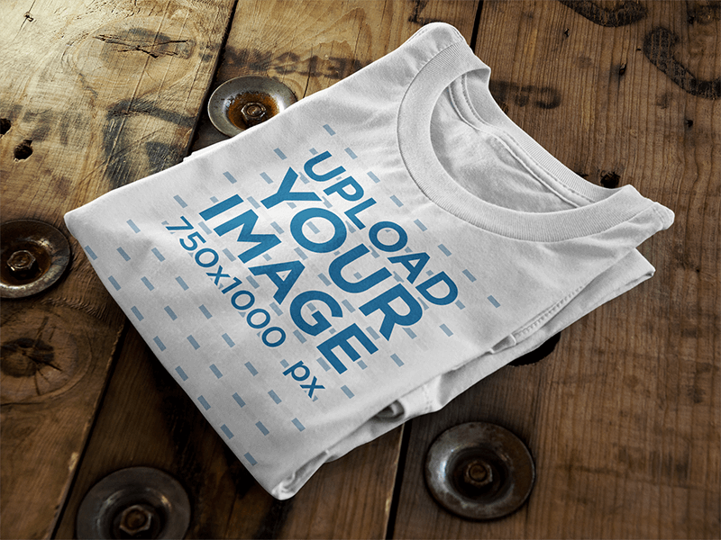 Folded T Shirt Mockup Sitting On Top Of A Wooden Table