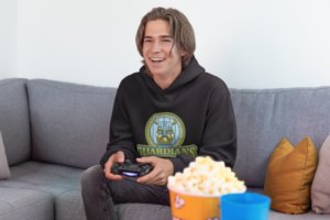 Pullover Hoodie Mockup Of A Joyful Gamer Man Playing Video Games On A Couch