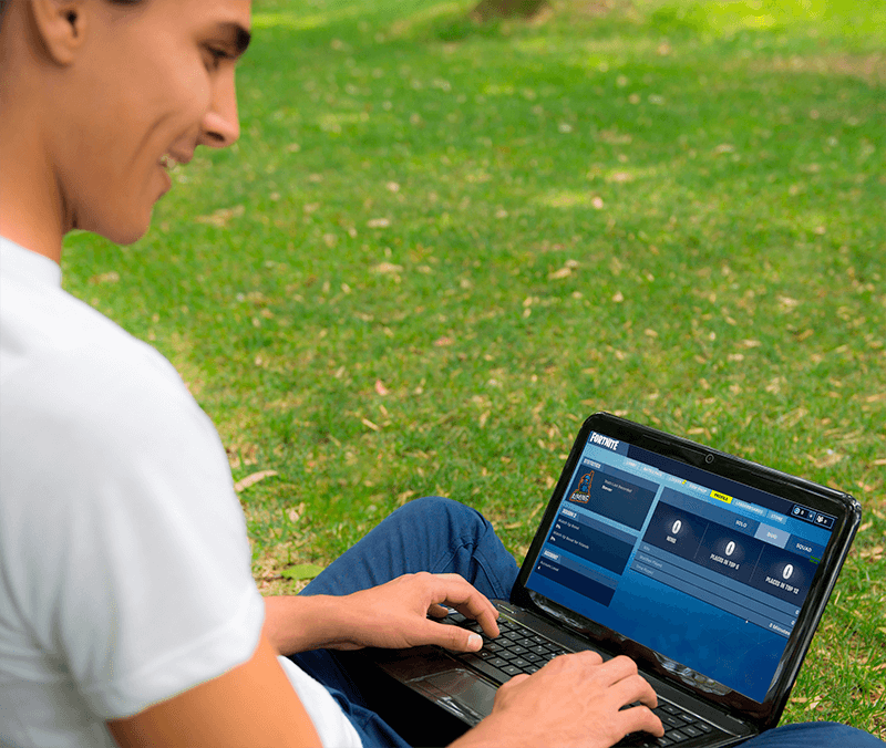 Young Man Sitting On Grass In Park And Using An Hp Laptop