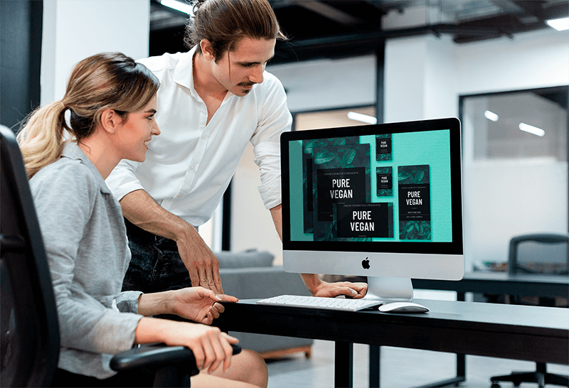 Man Coaching A Coworker Working On An Imac Mockup