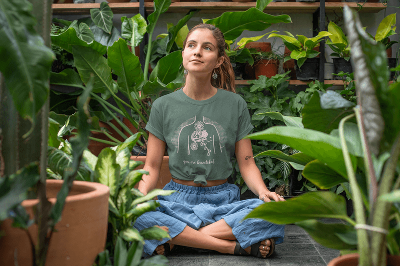 T Shirt Mockup Of A Relaxed Young Woman Sitting In A Greenhouse