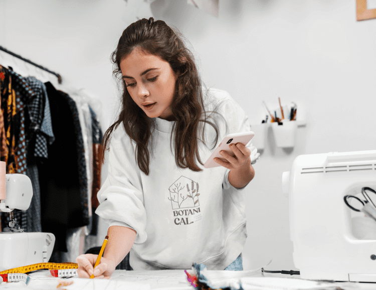 Sweatshirt Mockup Featuring A Woman Working At A Fashion Design Studio M8172 R El2 (1) (1)