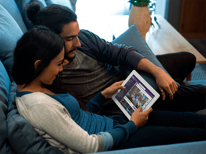 White Ipad Mockup In Landscape Position Of A Couple Lying On A Couch In Their Apartment