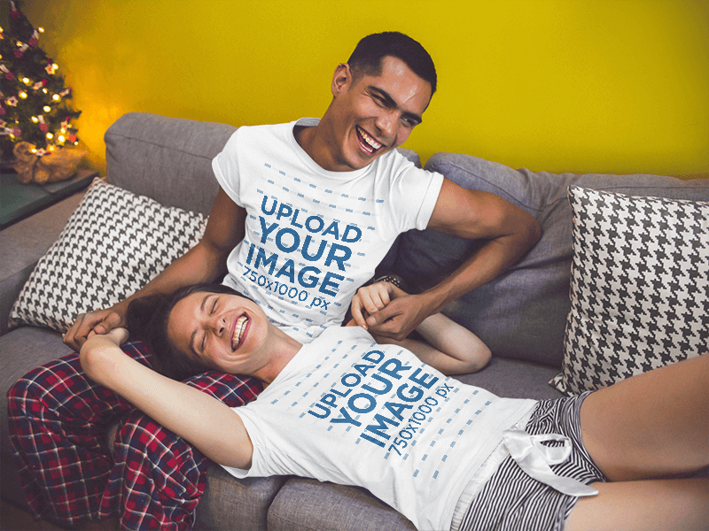 Couple Making Jokes Wearing Different Round Neck Tees Mockup Holding Hands In The Sofa