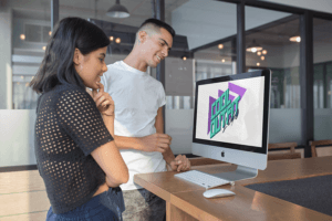Man And Woman Looking At An Imac Mockup In A Modern Office