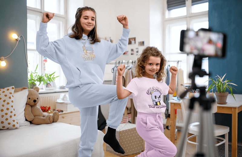 T Shirt And Hoodie Mockup Of Two Sisters Recording A Video