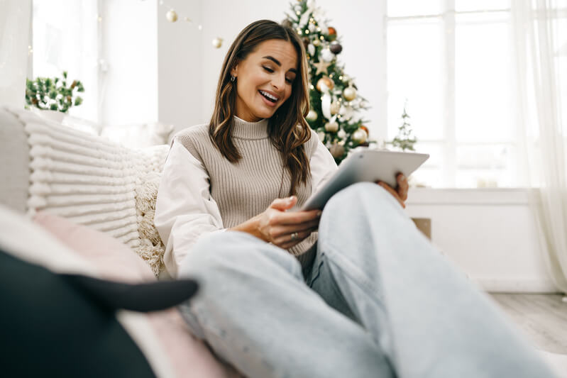 Beautiful Woman Relaxing On The Sofa With Digital Tablet At Christmas