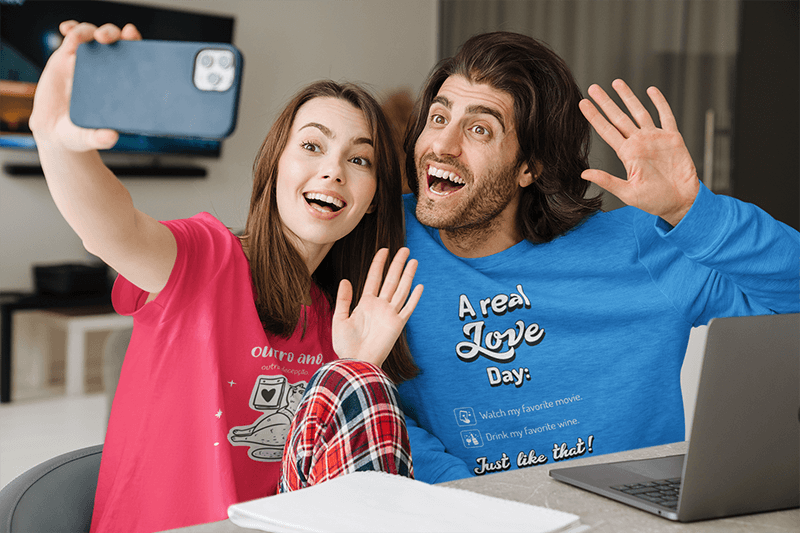 T-paita ja college-malli Hymyilevasta parista, joka ottaa selfietä kotona