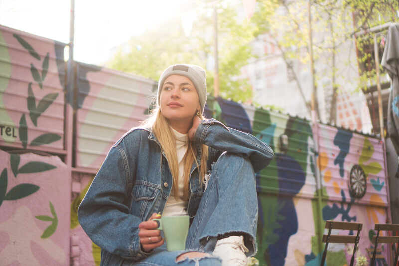 A young woman on an outdoor scenario enjoying her coffee brand