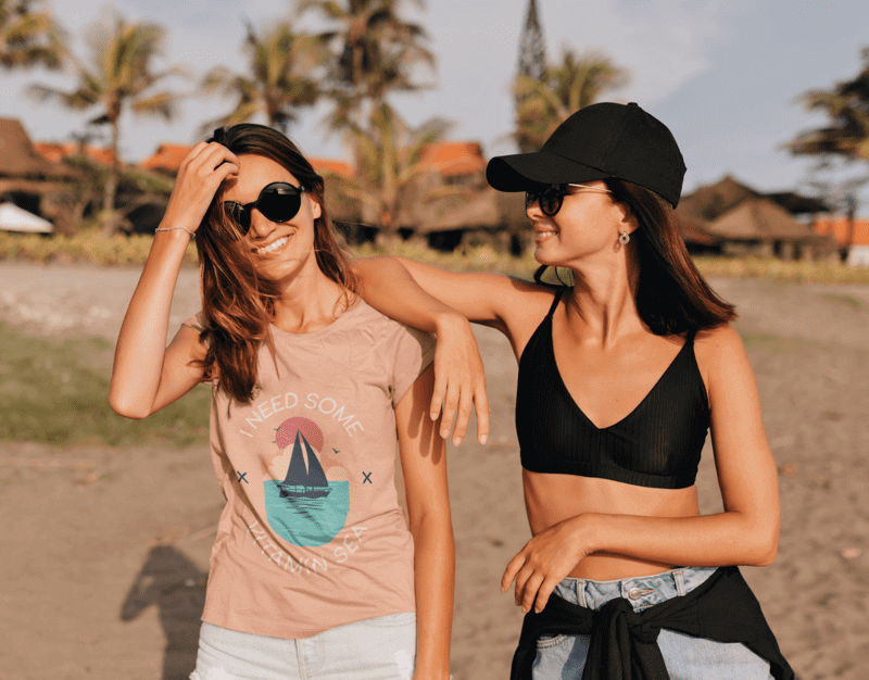 Two young women enjoying their summer sales at the beach wearing seasonal apparel