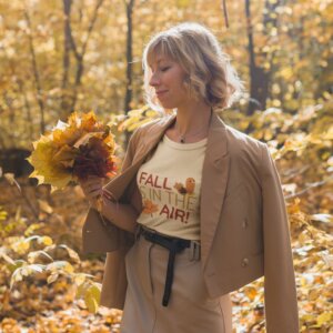 T Shirt Mockup Of A Happy Woman Wearing A Fall Shirt While Holding Autumn Leaves