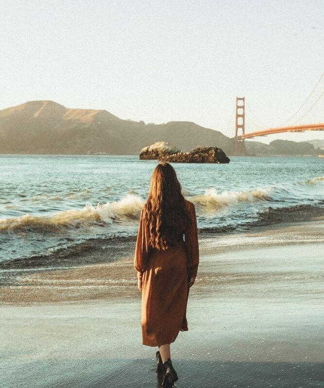 A Female Solo Travel Content Creator Strolling Along One Of The Beaches In San Francisco