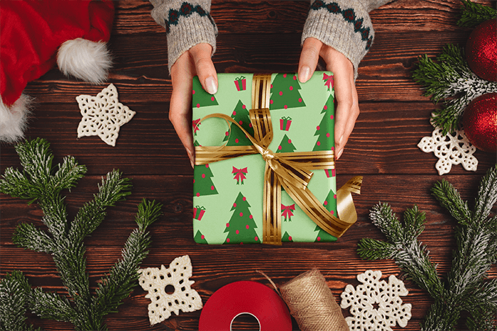 Wrapping Paper Mockup Featuring A Woman Holding A Gift Against A Christmas Themed Setting