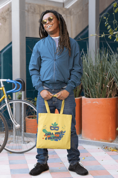 Tote Bag Mockup Featuring A Man Posing In Front Of Some Flowerpots