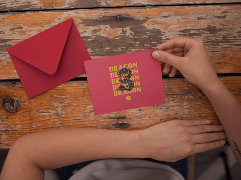 Invitation Template Held Near A Red Envelope On An Old Wooden Table