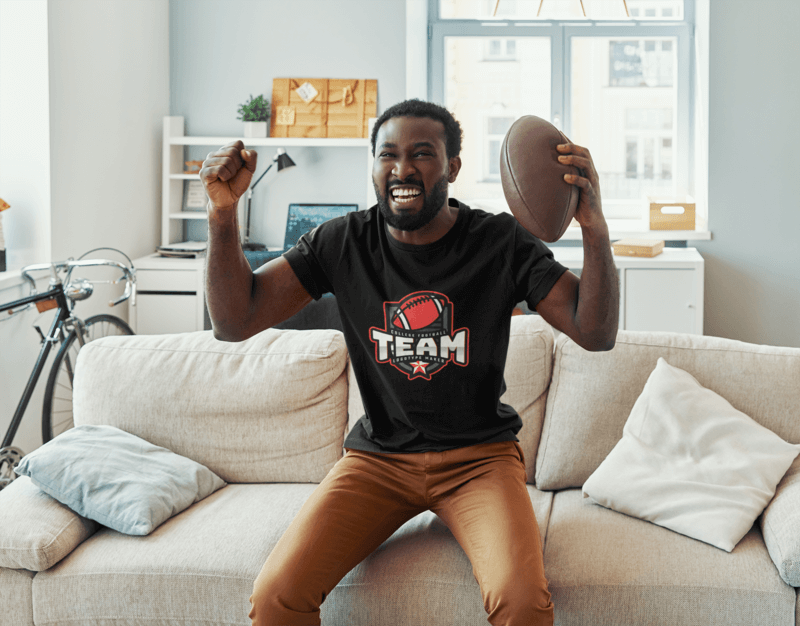 T Shirt Mockup Featuring An Excited Man Holding A Football Ball