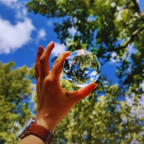 A Hand Holding A Bubble Of Water With Trees Around
