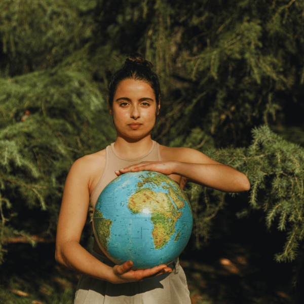 A Young Woman Holding A Globe In Her Hands Against A Green Background