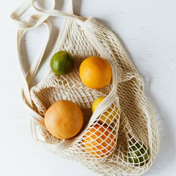 An Eco Friendly Tote Bag With Some Oranges Inside