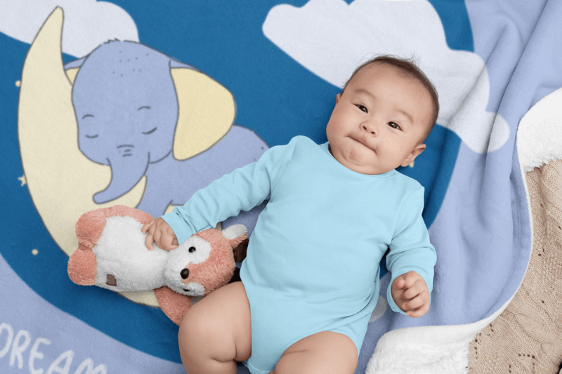 Mockup Of A Baby Wearing A Onesie Lying On A Fleece Blanket