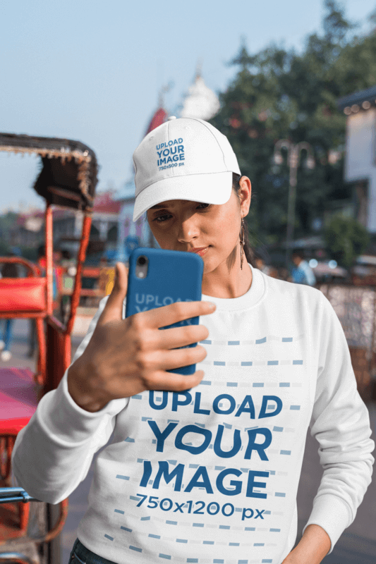 Sweatshirt And Dad Hat Mockup Featuring A Woman Taking A Selfie