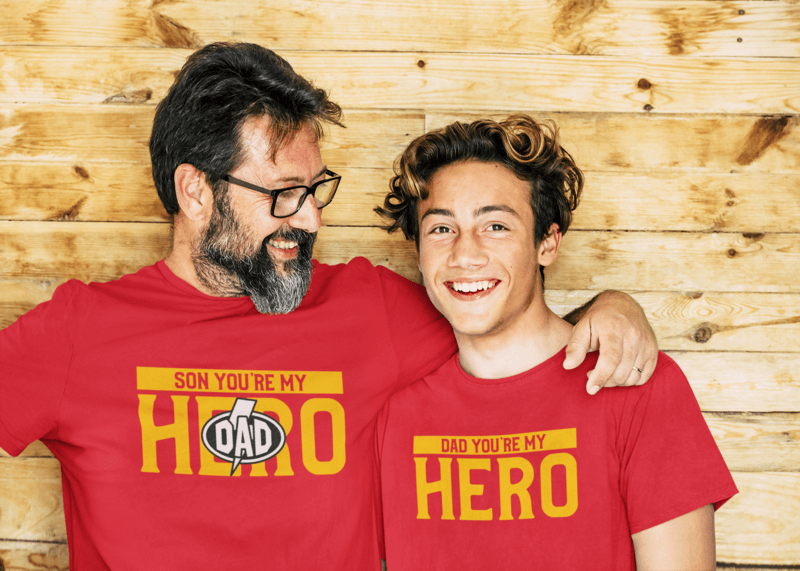 T Shirt Mockup Featuring A Bearded Man Posing With His Son Against A Wooden Wall