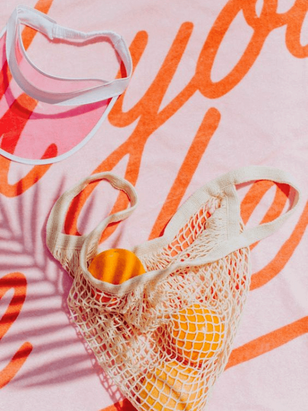 An Aesthetic Colorful Beach Towel And An Organic Tote Bag With Some Oranges On It To Illustrate A Summer Items Blog