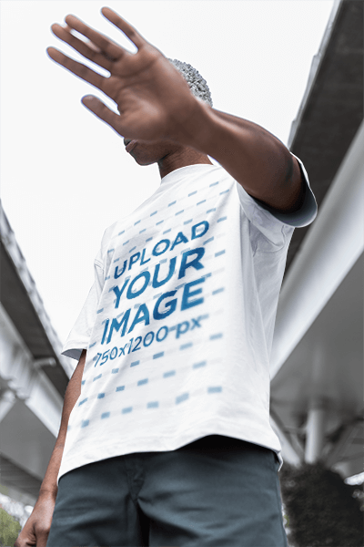 Oversized T Shirt Mockup Of A Man Posing In The Street While Covering His Face