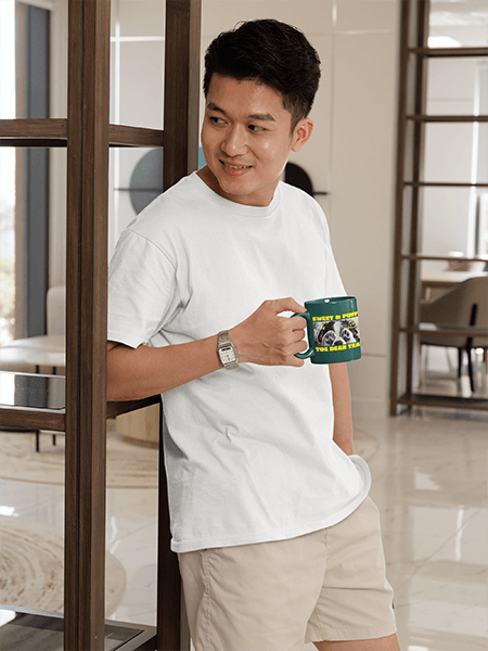 Gildan T Shirt Mockup Of A Smiling Man Posing In A Room With A Coffee Mug