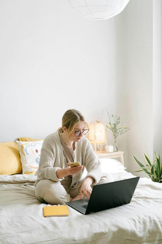 Photo Of Woman Sitting On Bed While Using Black Laptop By Pexels