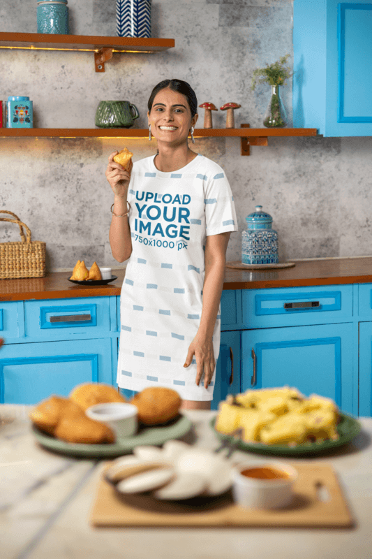 T Shirt Dress Mockup Featuring A Cheerful Woman Holding A Snack In A Kitchen