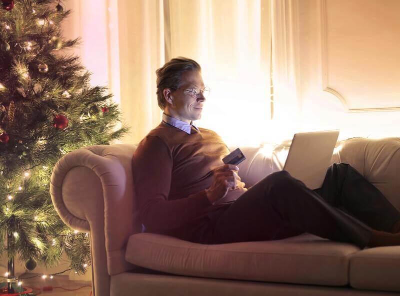 Photo Of A Man Online Shopping Featuring A Christmas Tree In The Background By Pexels