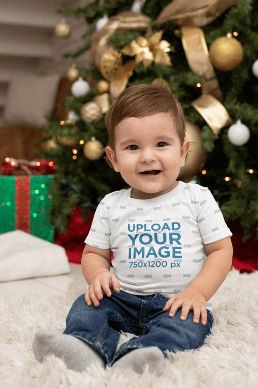 T Shirt Mockup Featuring A Baby In Front Of A Christmas Tree