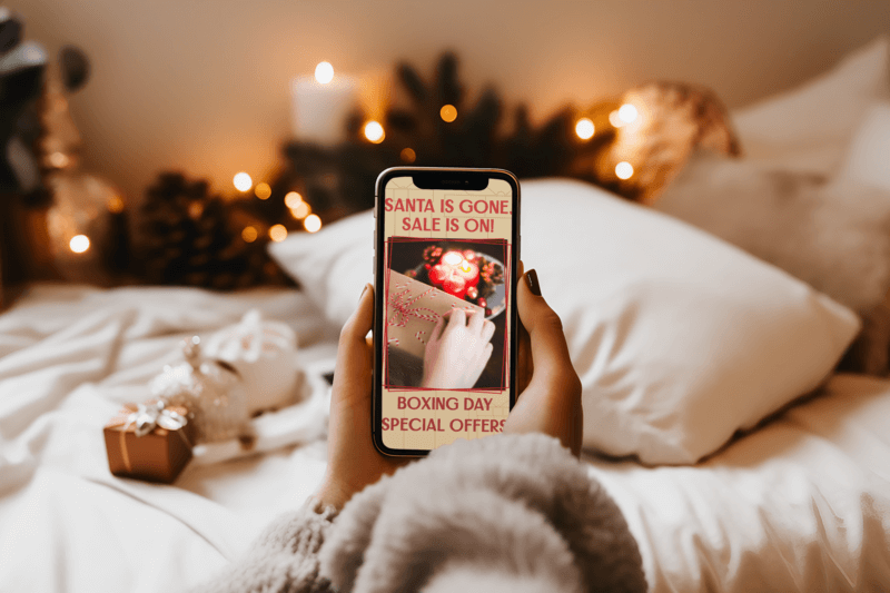 Christmas Mockup Of A Woman Using Her iPhone On Her Bedroom Viewing A Christmas Promo