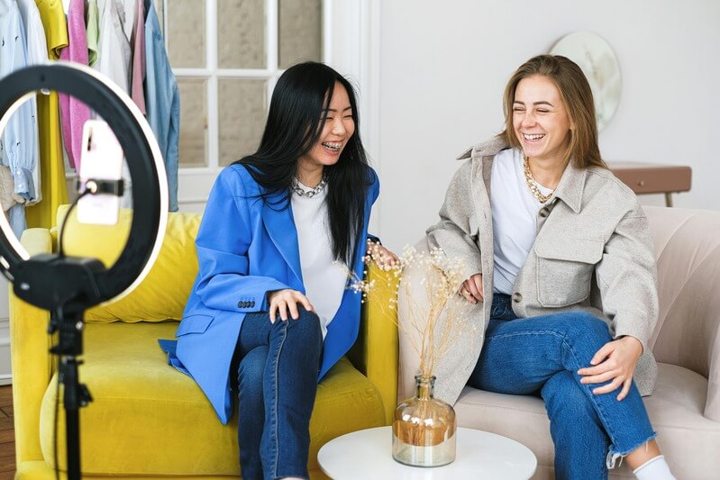 Photo Of Two Women Sitting In Armchairs Smiling While Vlogging By Pexels