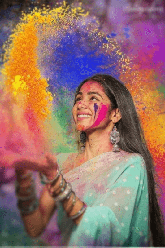 A Beautiful Young Woman Wearing A Turquoise Traditional Indian Outfit, Holding Gulaal Powders And Joyfully Throwing Them Into The Air