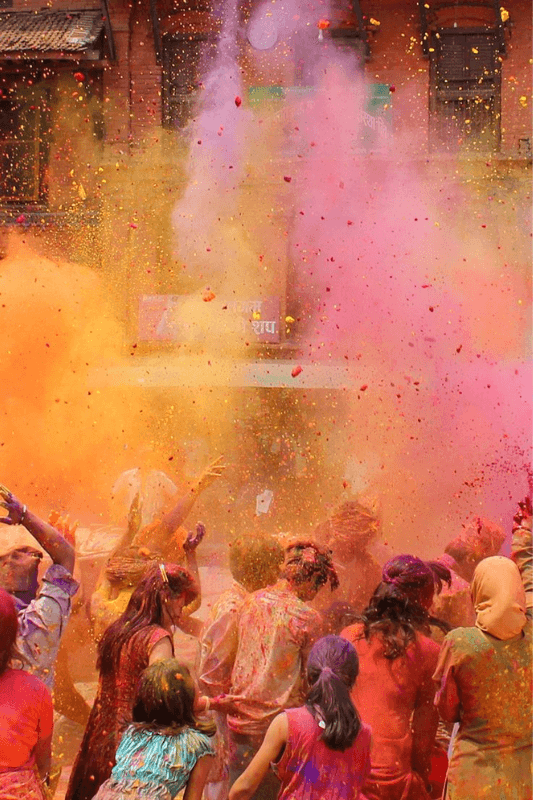 A Front View Of People Celebrating Holi In A Street In India, Seen From Behind