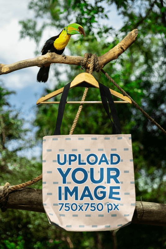 Mockup Featuring A Tote Bag Hanging From A Tree Branch With A Toucan