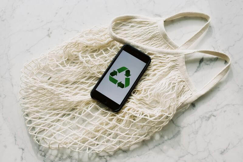 Photo Of A Mobile Phone With Green Recycling Sign And Mesh Bag By Pexels