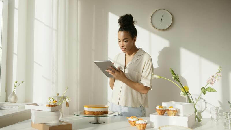 Photo Of A Woman Making An Order On Her Tablet While Standing Near Desserts By Pexels